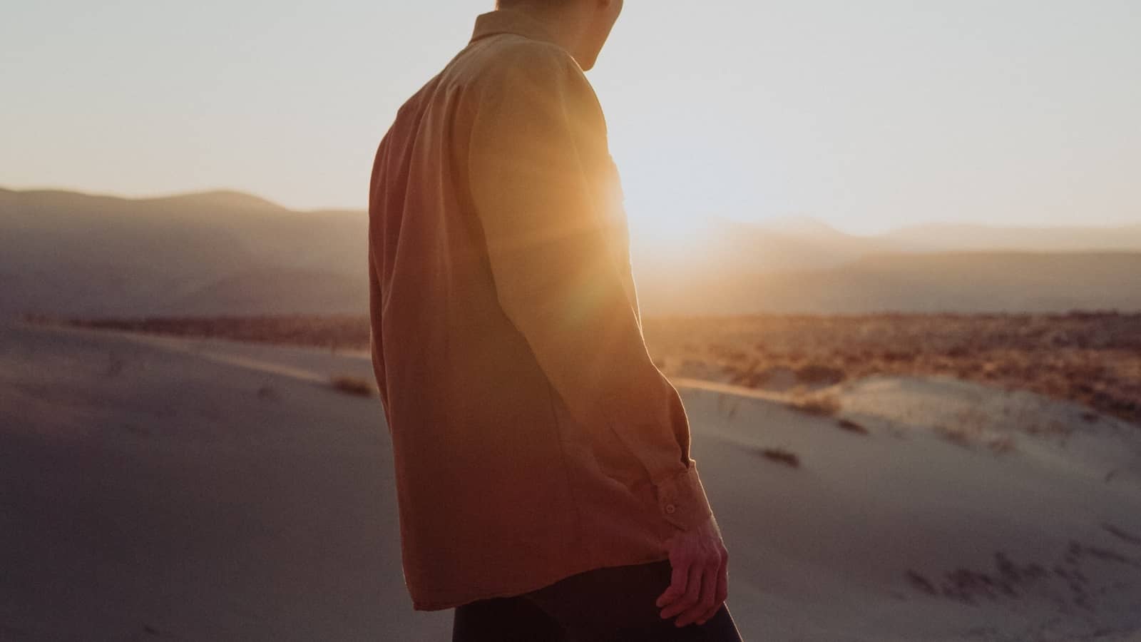 Mann mit Frühlings-Outfit blickt auf Sonnenuntergang