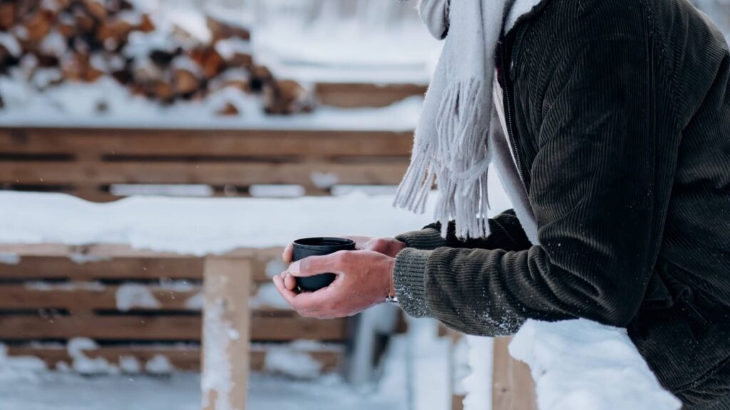 Herren in Winter-Outfit in Schneelandschaft mit Tasse