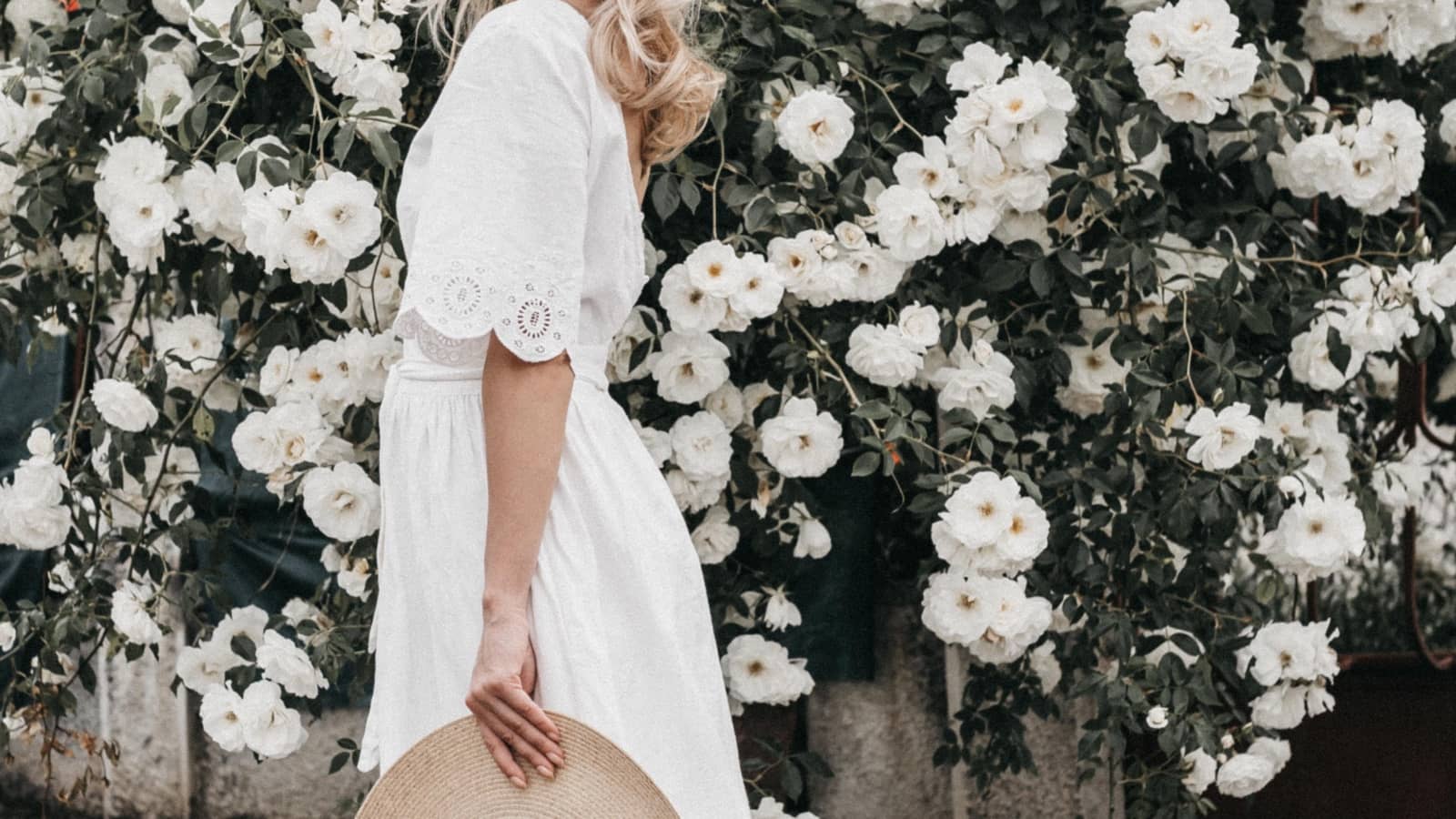 Frau in weißem Frühlings-Outfit vor blühenden, weißen Blumen