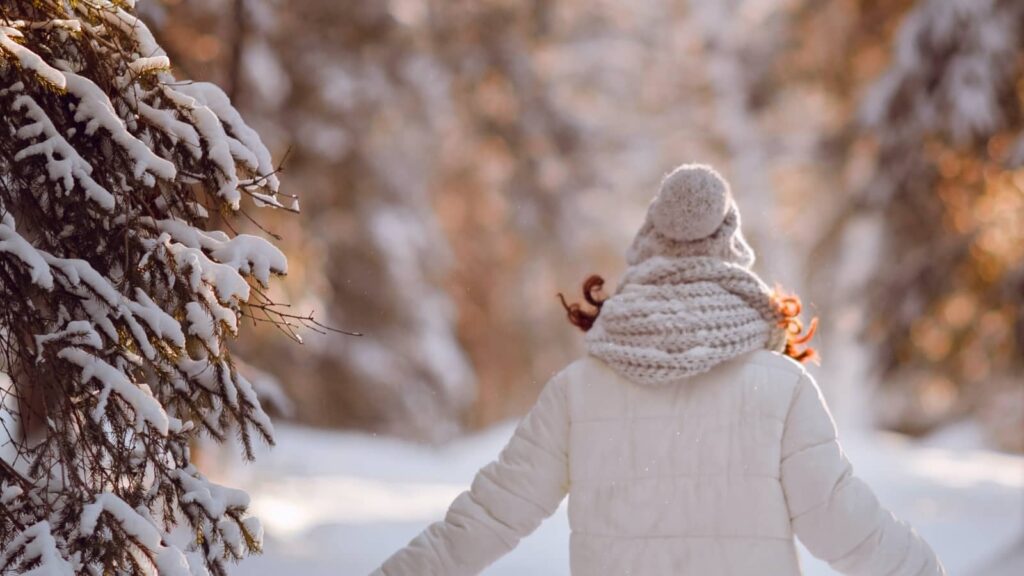 Frau in Winter-Outfit vor Schneelandschaft