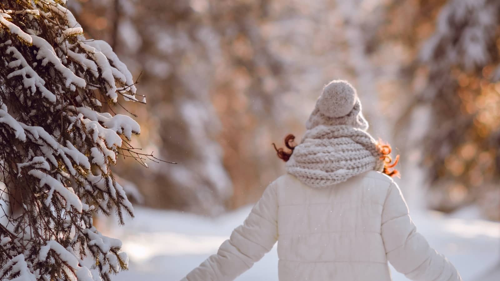 Frau in Winter-Outfit vor Schneelandschaft