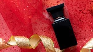 Maskuliner Parfum-Flakon mit Weihnachtsschmuck auf rotem Hintergrund